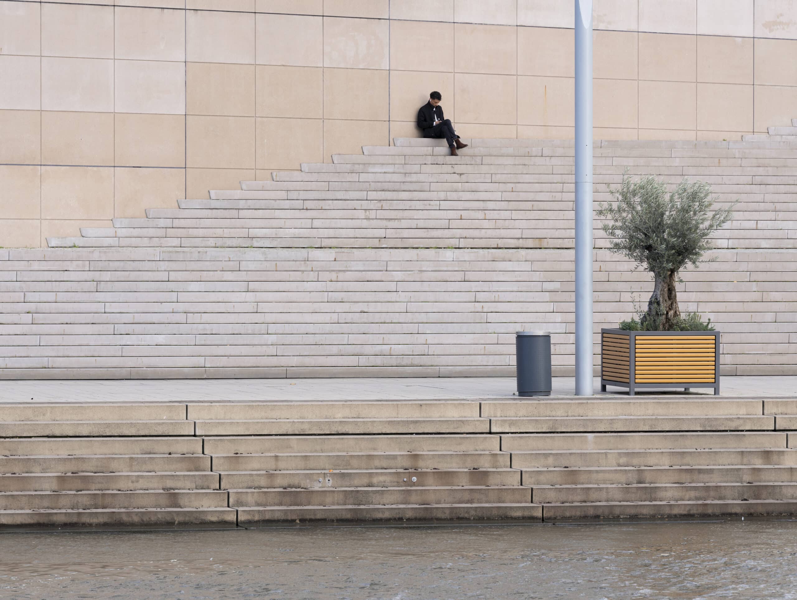 Un jeune homme assis tout en haut de plusieurs marches d'escalier