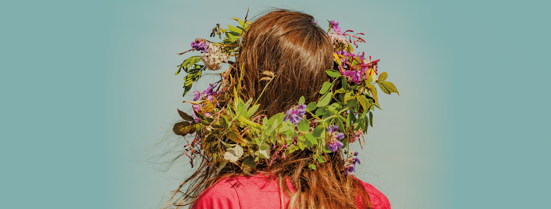 Visuel de la fête de la Saint-Jean et du solstice d'été avec une femme de dos, cheveux longs lâchés et une couronne de fleurs violettes sur la tête