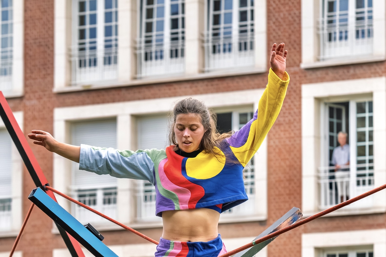 Une dame habillée de vêtements colorés en train de marcher sur un fil d'équilibriste