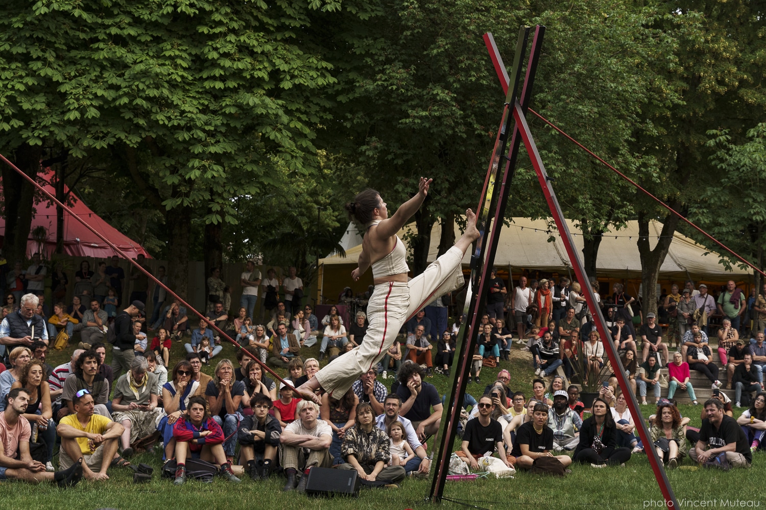En arrière-plan, une foule importante regarde l'artiste Theresa Kuhn en train de marcher sur un fil de funambule.