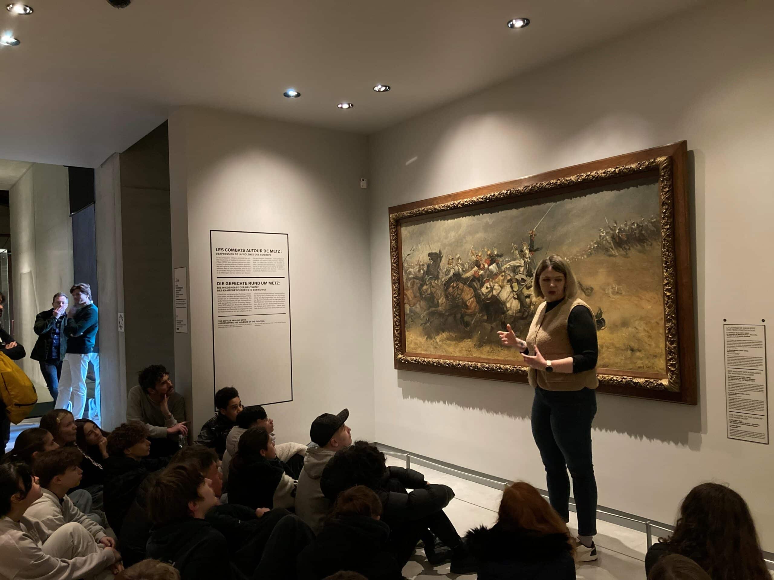 Des élèves en train d'admirer une peinture du Musée représentant la bataille de Rezonville en 1870.