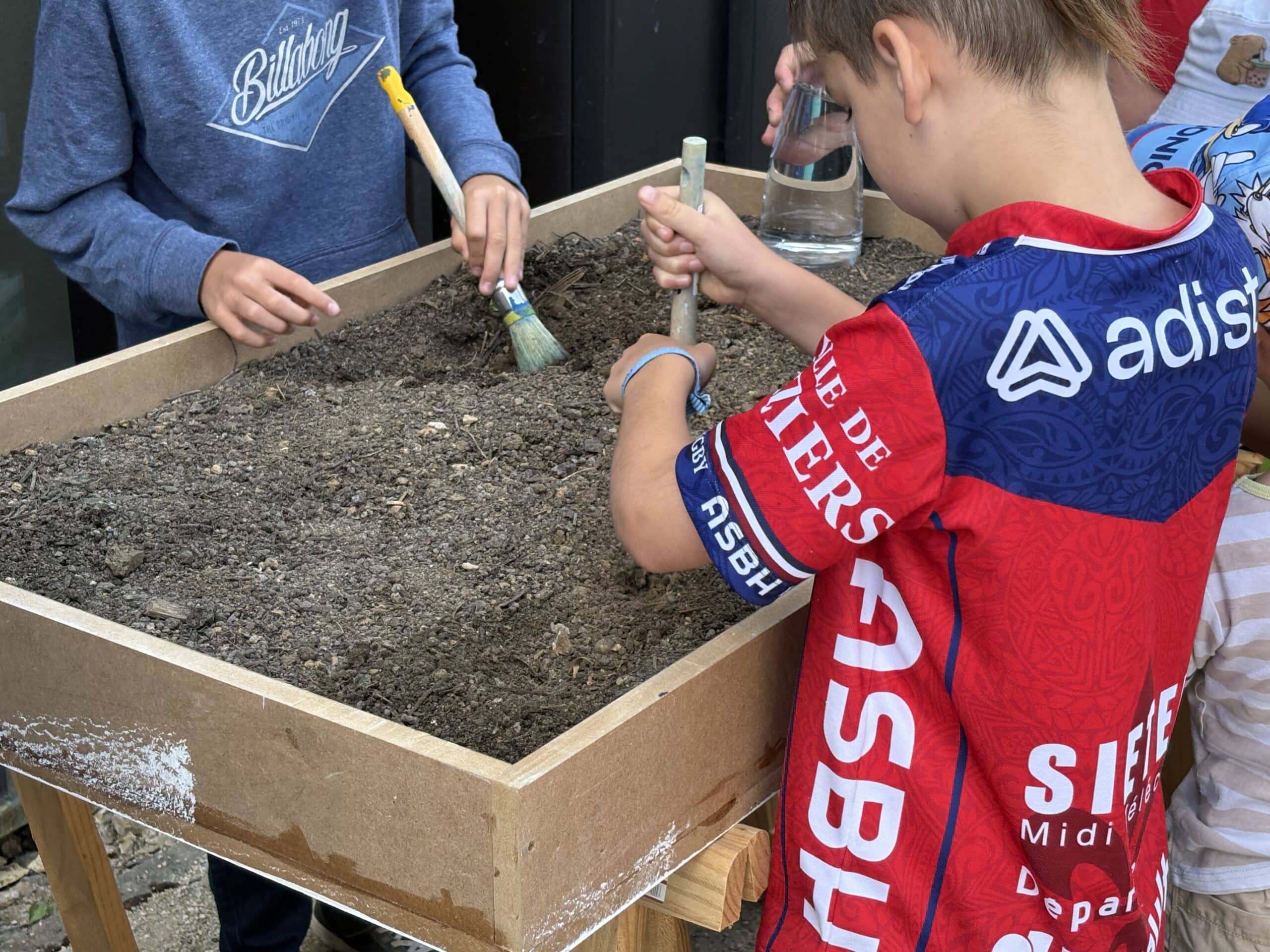 Enfants fouillant de la terre dans le cadre d'un atelier d’archéologie au sein du musée.