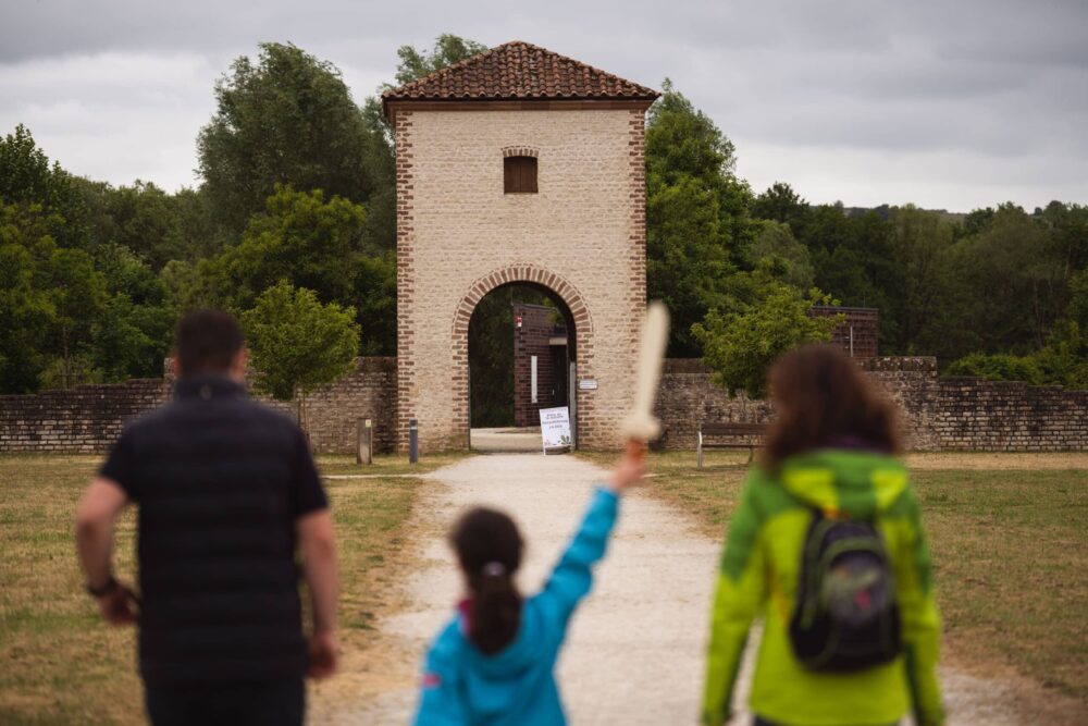 Des visiteurs se dirigent vers la porte de la villa romaine. une petite fille tient un glaive dans sa main.