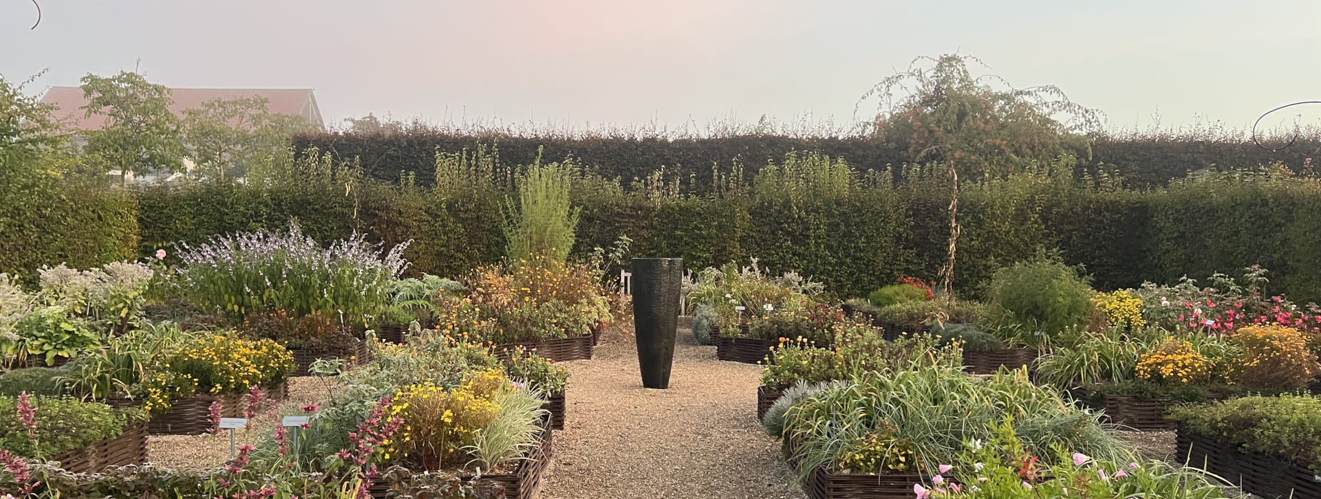 Le jardin des fleurs à croquer avec sa fontaine verticale noire au centre de l'allée, jardin en carrés potager en acier corten.