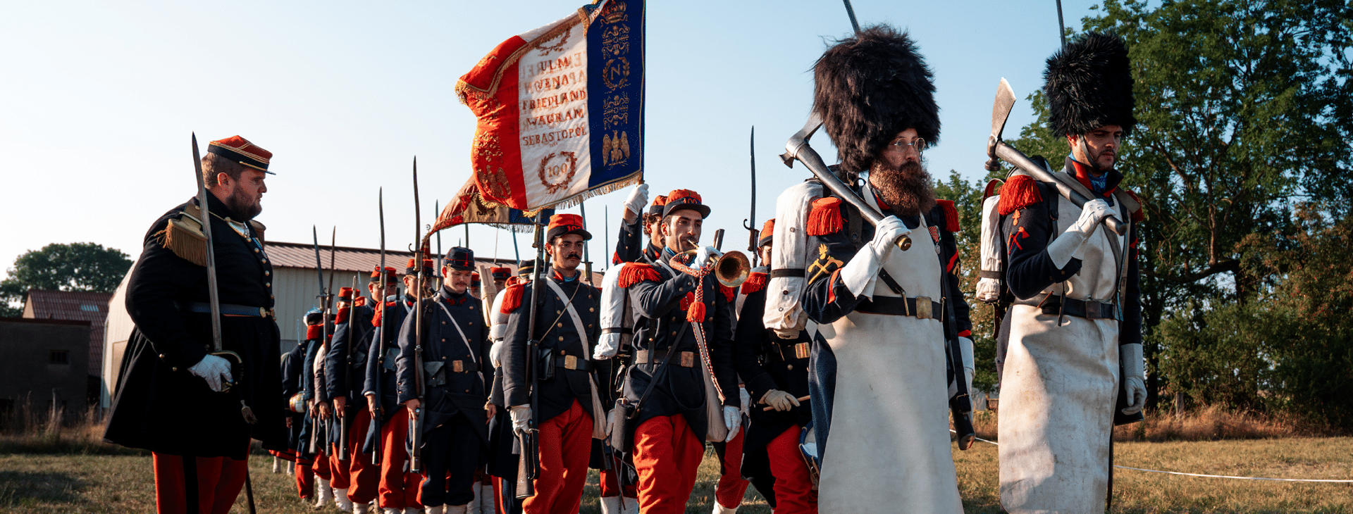 Visuel montrant des soldats de la Guerre de 1870 vêtus d'un pantalon rouge et une veste bleu et défilant avec le drapeau français.