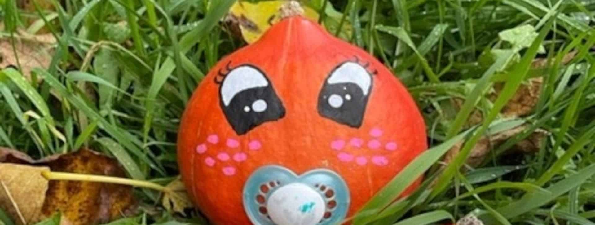 Tête de bébé dessiné sur un potimarron avec une tétine à la place de la bouche.