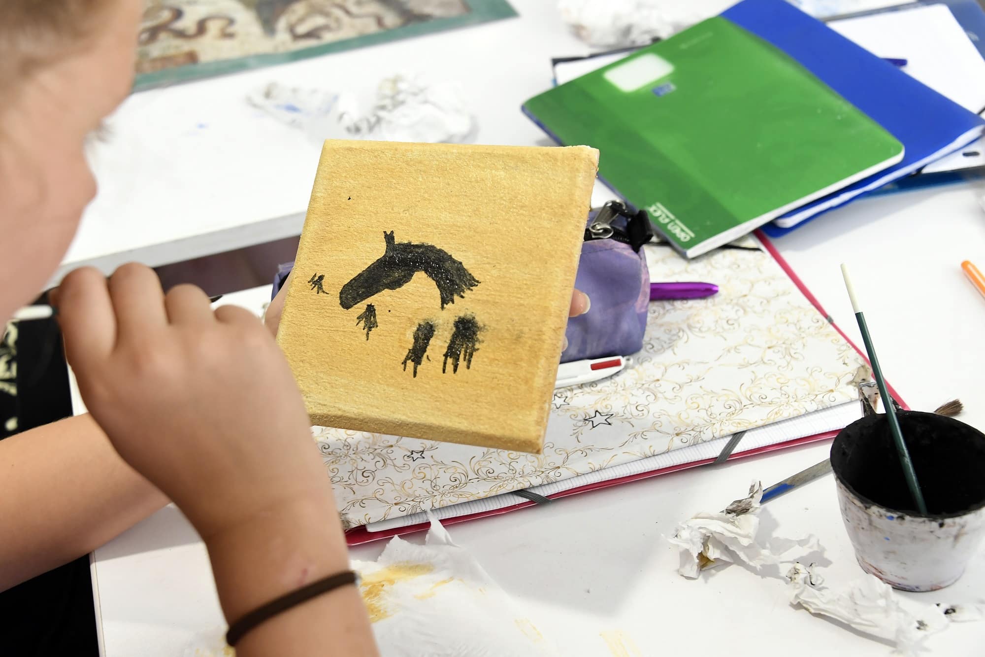 Visuel d'un enfant en train de réaliser une silhouette de cheval en fresque sur un carreau