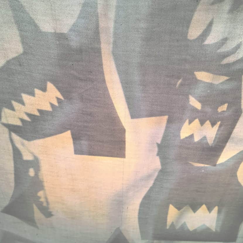 Ombres chinoises de masques grimaçants et profils de loups aux dents acérées.
