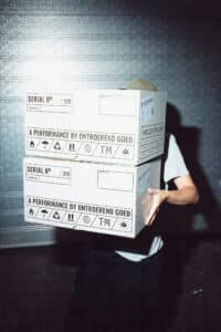 Un jeune homme porte deux gros cartons devant lui